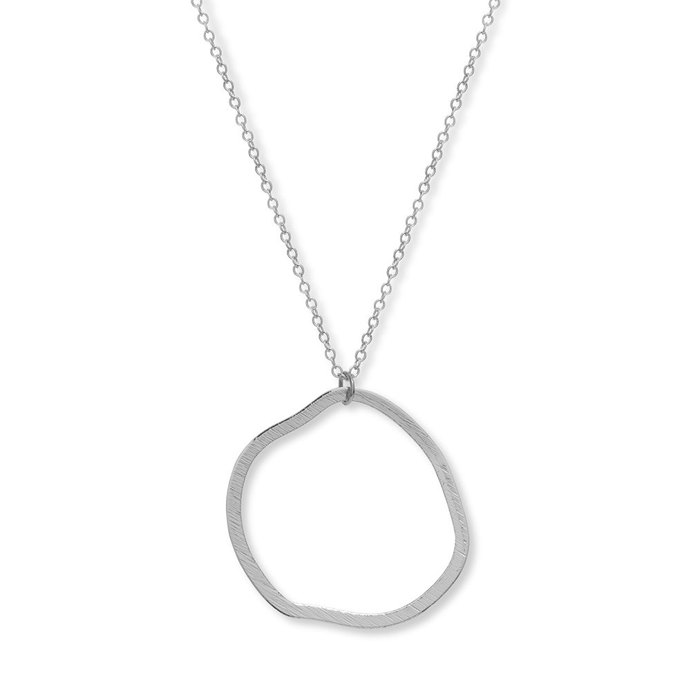 A close up of a silver chain and round silver circle pendant, the circle isn't perfectly round and has an abstract feel to it.