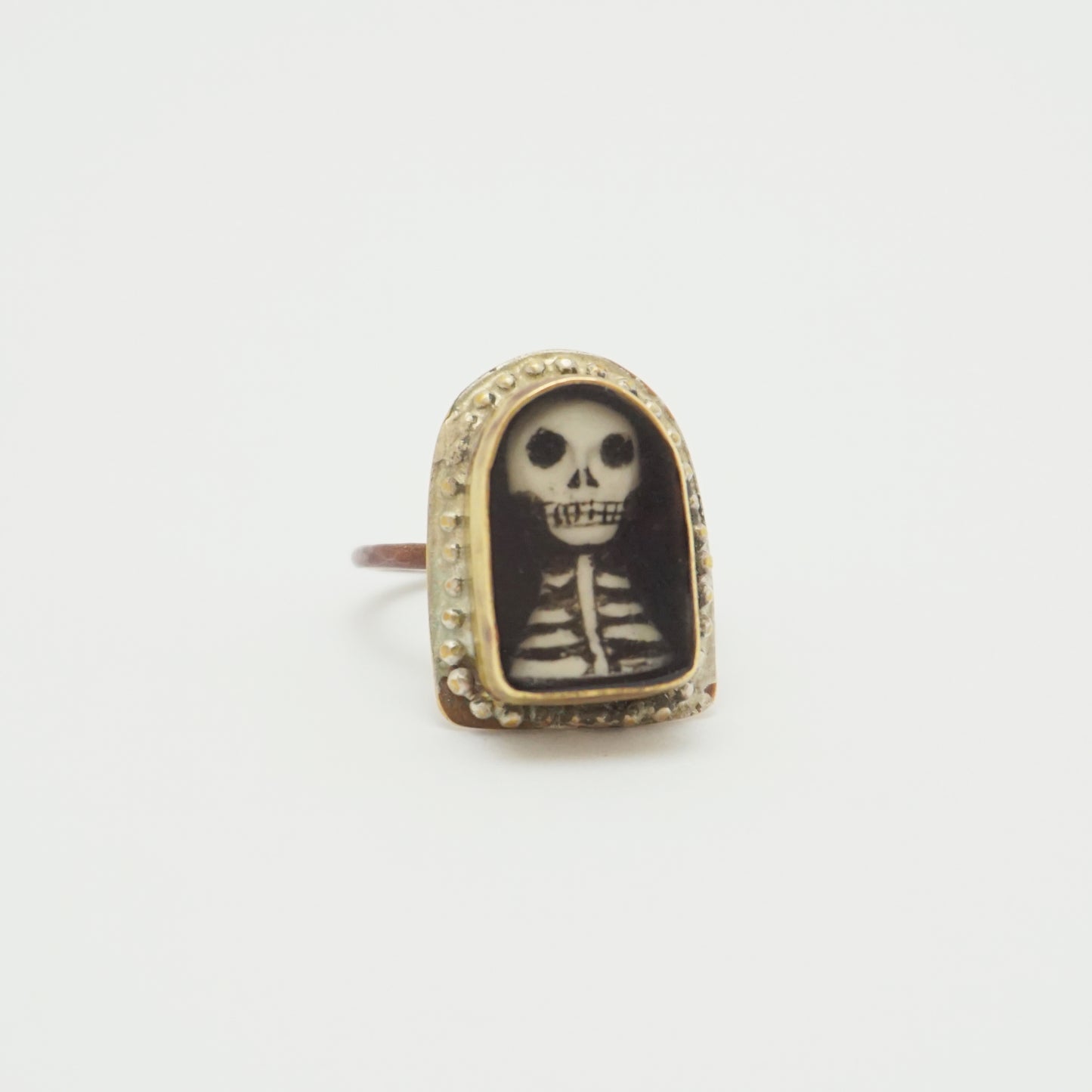 Ring with a hand painted skeleton design in a gold bezel on a white background