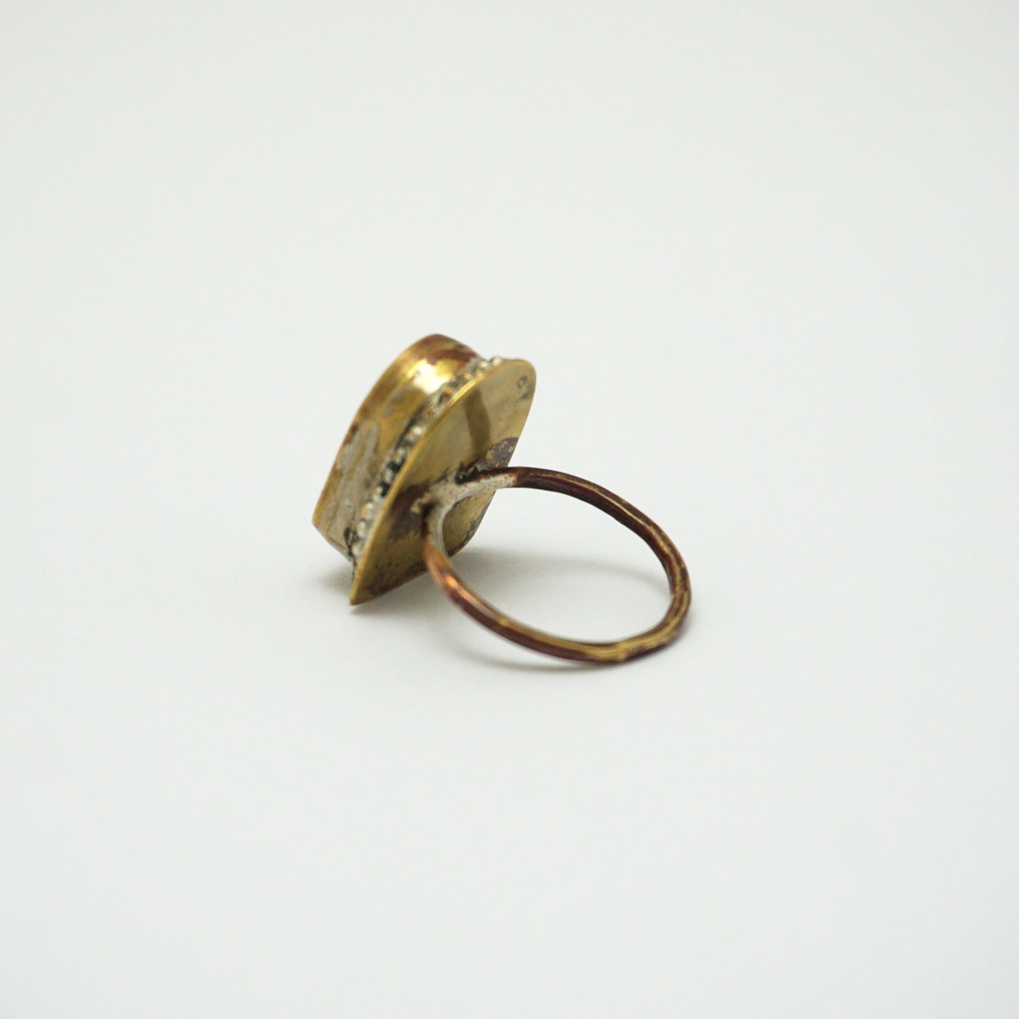 The back of a brass ring a light grey background