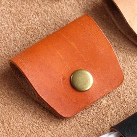 A tan leather cable wrap with a brass popper.