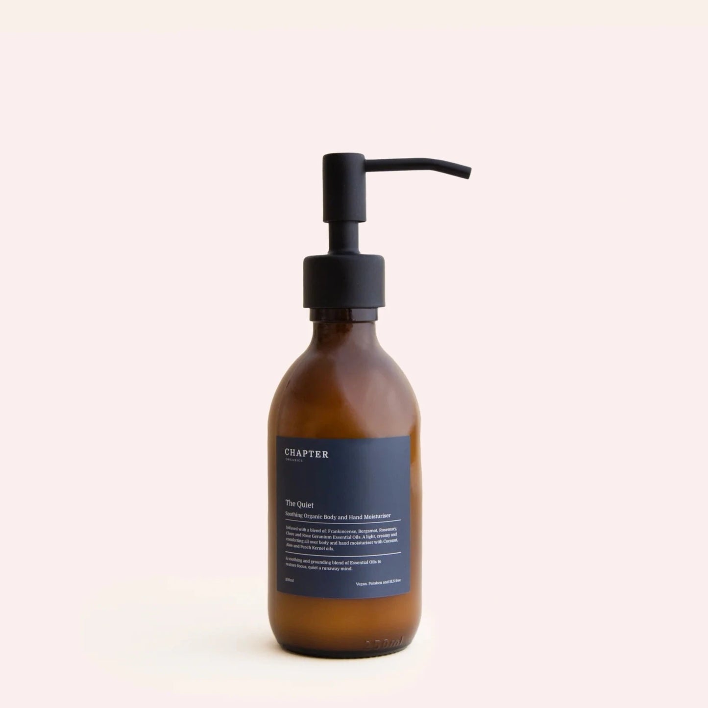 A brown glass bottle with a black pump dispenser, labelled "CHAPTER ORGANICS" in white text. The label features a description of the product and its benefits, set against a light beige background. The overall aesthetic is minimalist and elegant.