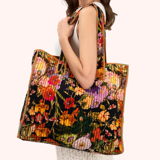 Woman holding a colorful floral tote bag on a white background
