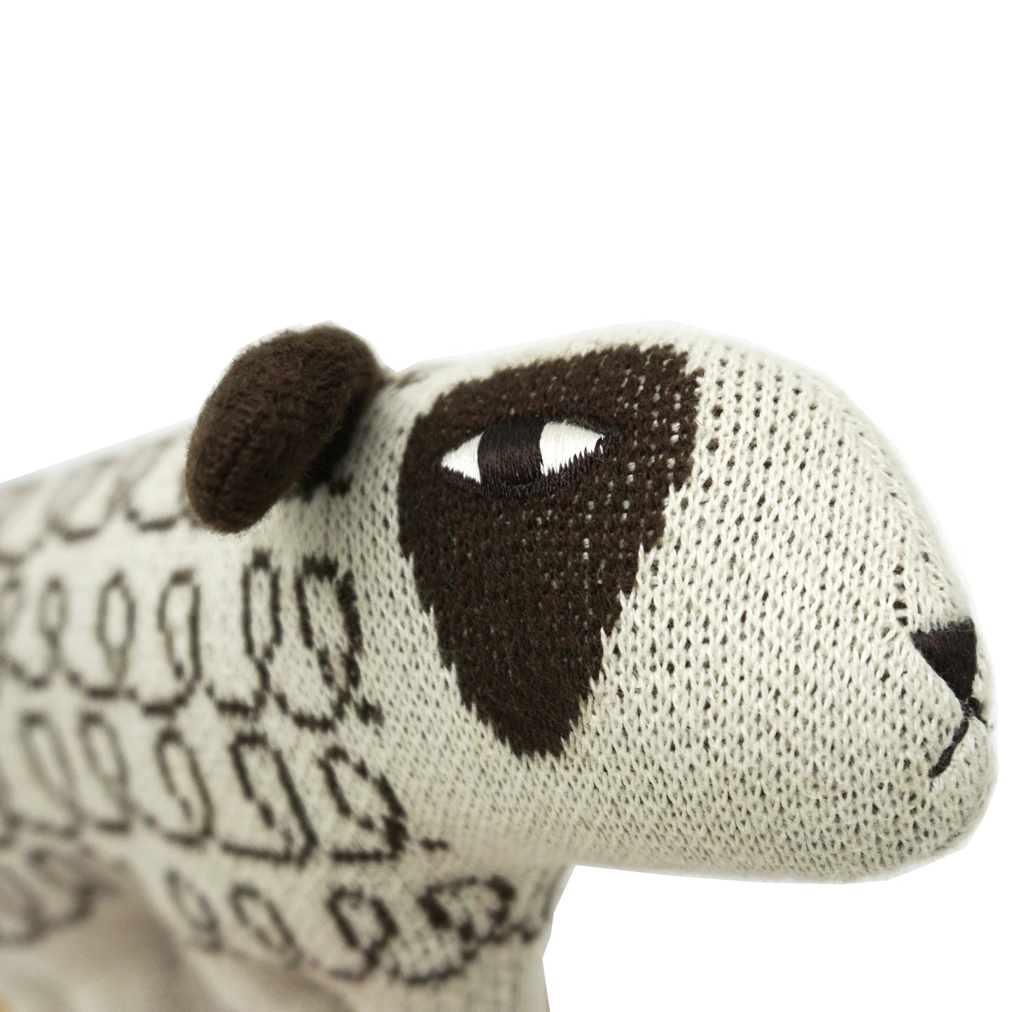 A close up shot of the face of a stylised stuffed cream and brown soft toy sheep with a patterned body and big brown ears.