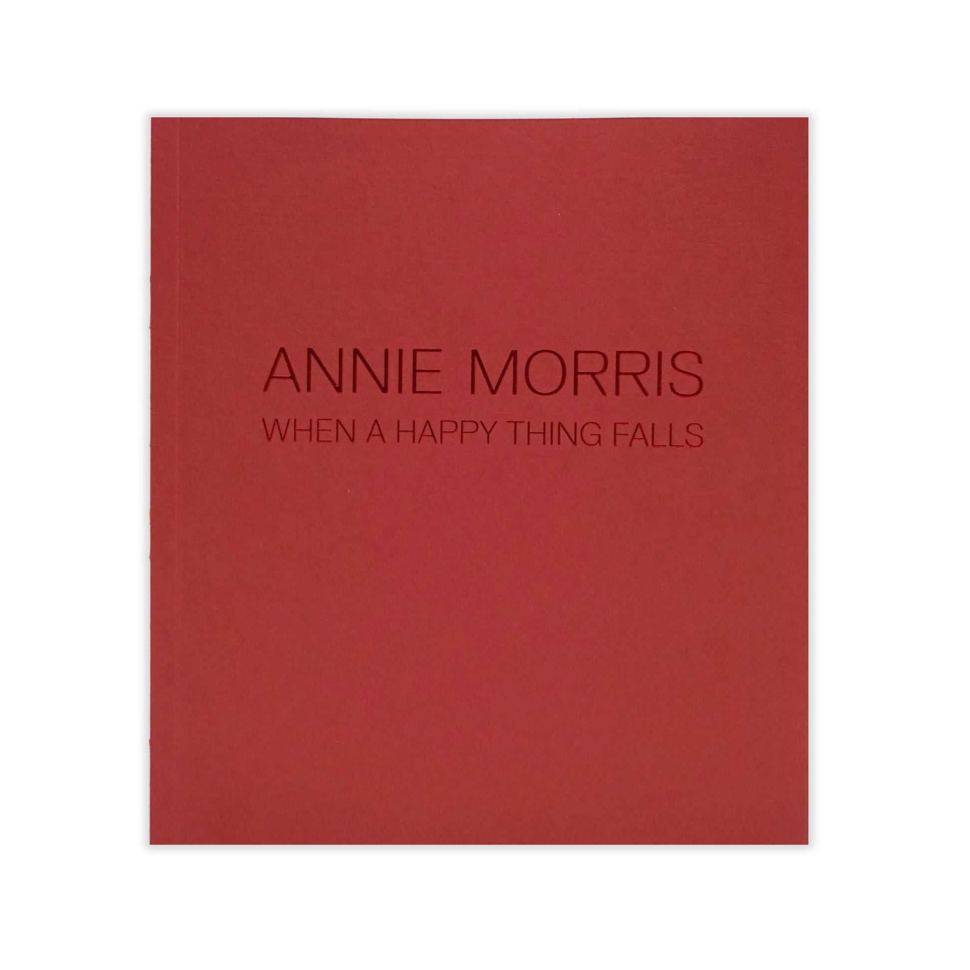 A deep red book cover featuring the embossed title "ANNIE MORRIS" and the subtitle "WHEN A HAPPY THING FALLS" in a modern, sans-serif font. The design is minimalist, with no additional images or text.