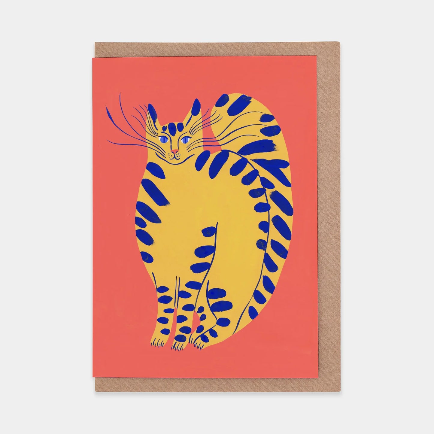 A vibrant greeting card featuring a stylised yellow cat with blue stripes, set against a coral background. The cat has long whiskers and a playful expression, exuding a whimsical and artistic charm. The card is bordered with a natural kraft paper.