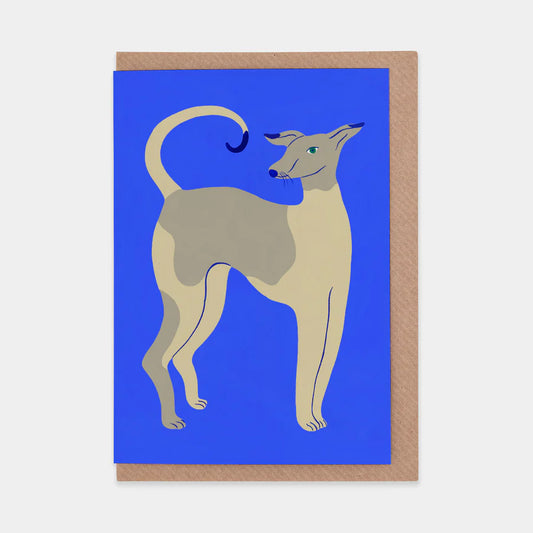 A greeting card featuring a stylised illustration of a dog against a bright blue background. The dog, with a light tan and grey coat, stands gracefully with its tail curled and a playful expression. The card has a brown kraft paper border.