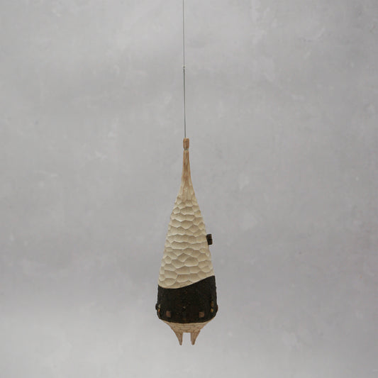 Decorative hanging wooden house with textured design on a plain background. The house has four legs and wooden windows, and is shaped almost like a beehive.