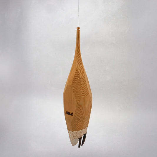 Decorative hand carved wooden house shaped like a small tower on a plain background. The house has legs, windows and a thin chimney which thread is coming out of to hang the house. The house looks to be made from an oak coloured wood.