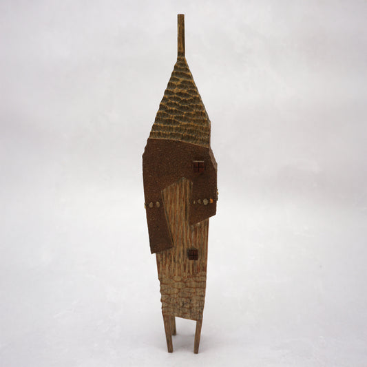 A pointy wooden house with a hand carved roof and body. The house has four legs and small wooden windows on the front.