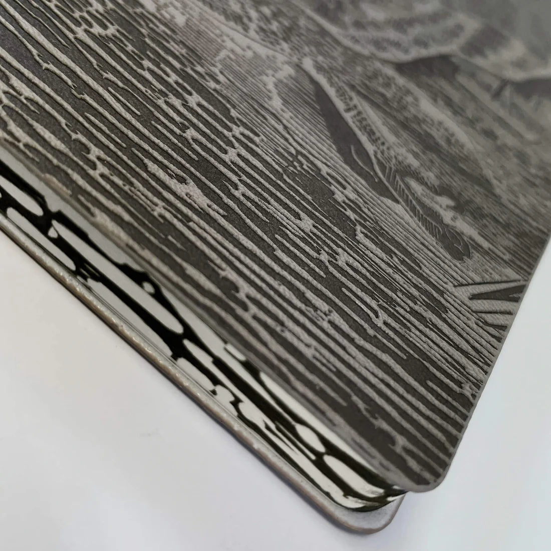 A close-up view of the edge of a book, featuring a textured cover with intricate black and white illustrations. The design includes wavy lines resembling water, creating a visually striking pattern against the light background.