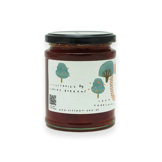 A glass jar with a black lid and white label featuring illustrations of trees and a deer shelter.