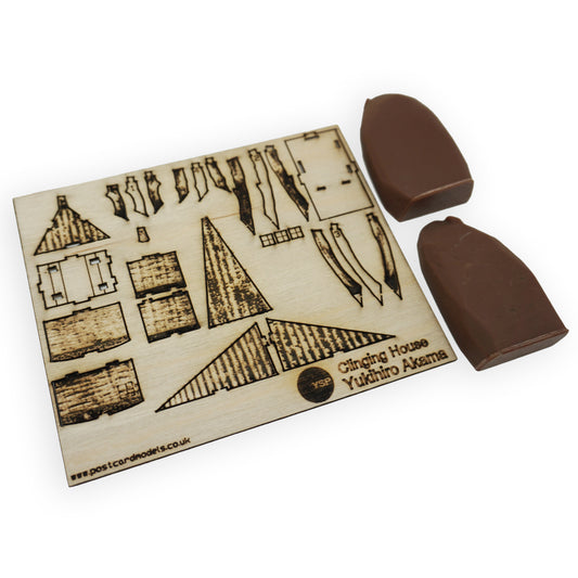 A flat lay laser cut sheet of pop-out components that create the Clinging House model. The pack also includes a 3D printed brown bolder.