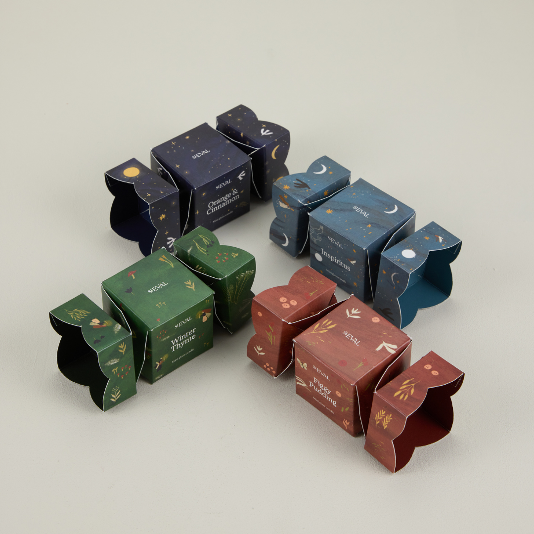 Set of decorative Christmas cracker boxes with various designs on a light grey background.