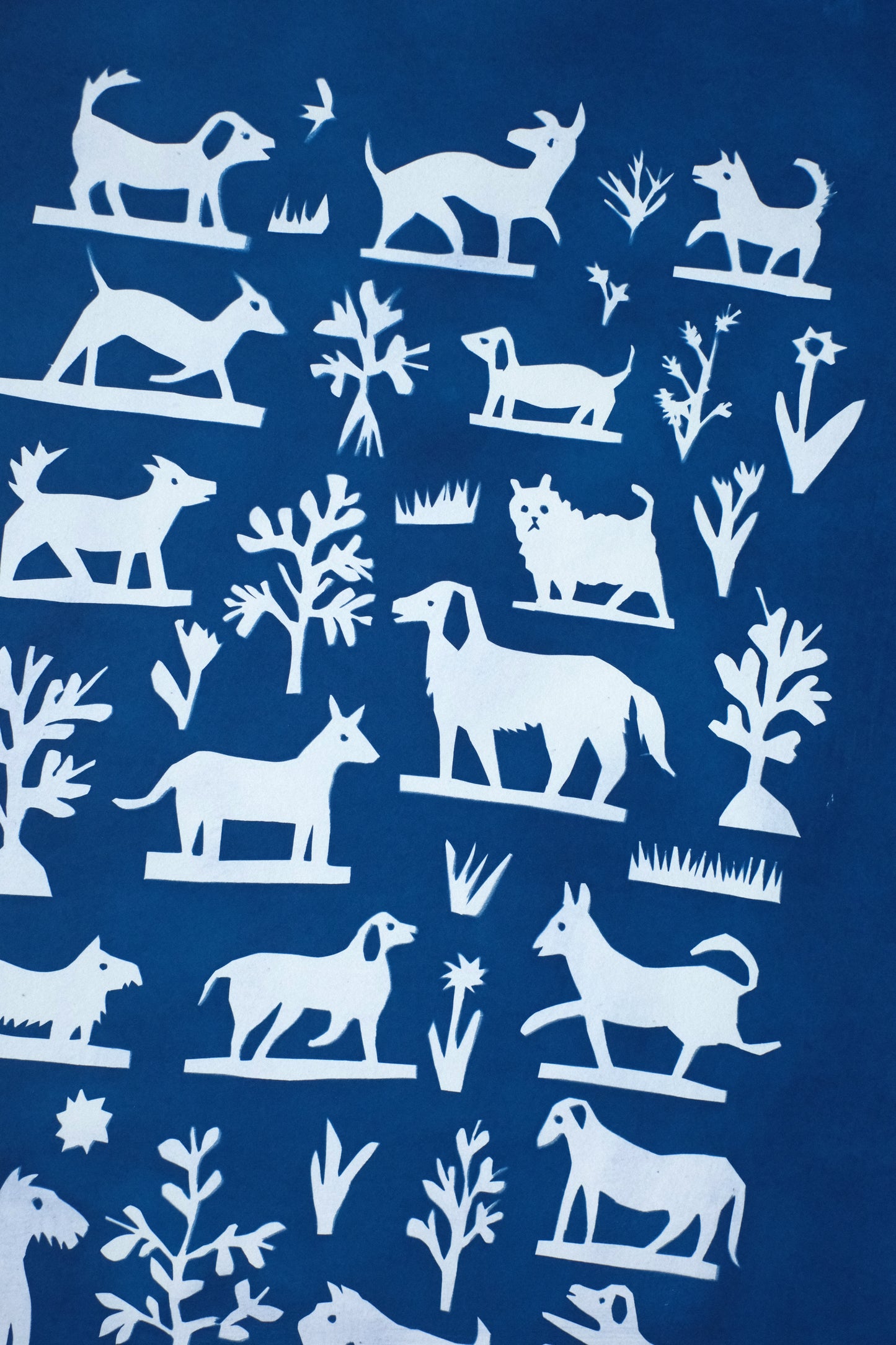 A blue background features a collage of white silhouettes depicting various dogs and trees. The designs are arranged in a grid pattern, showcasing playful and stylised representations of animals and nature.