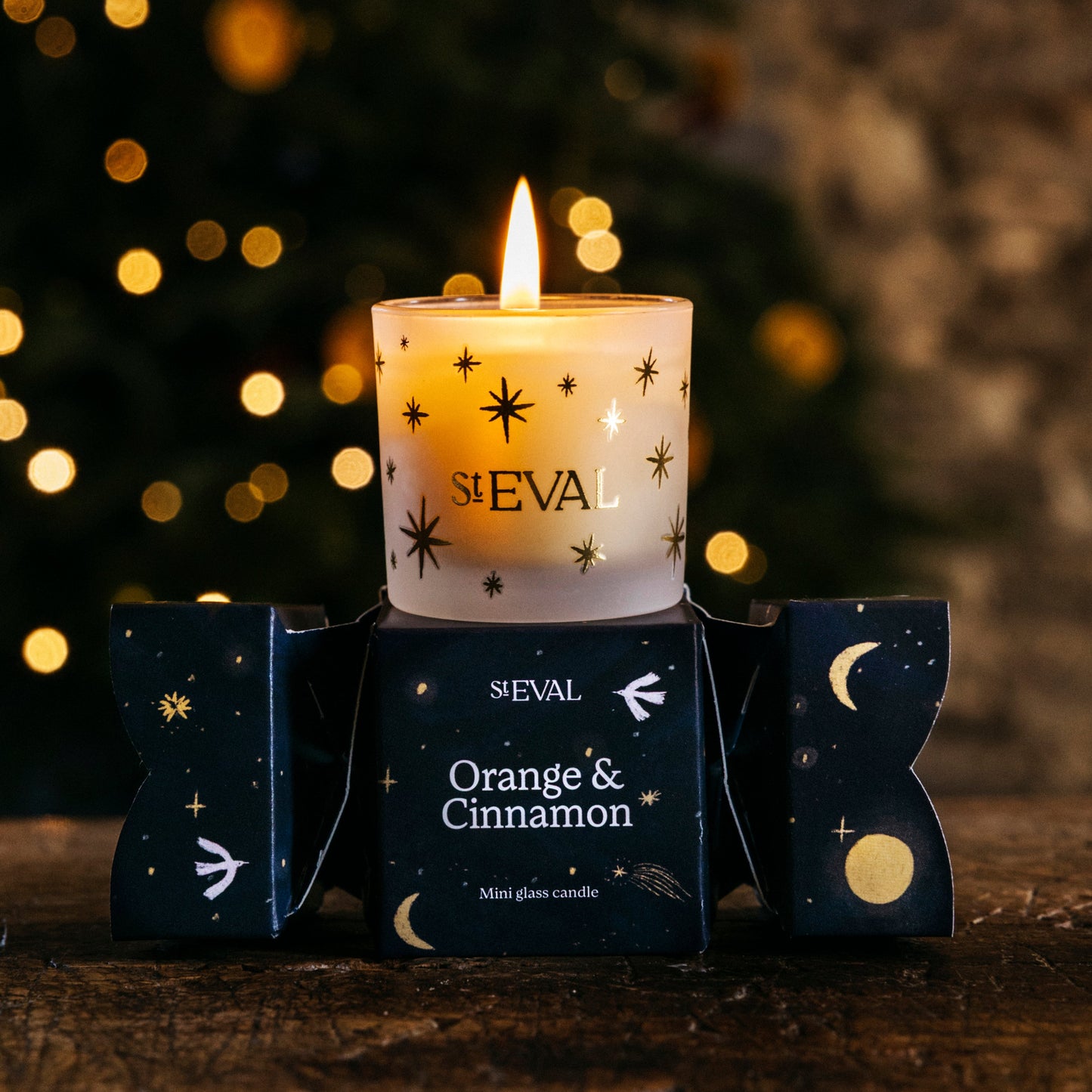 Sleval candle with 'Orange & Cinnamon' scent in front of a blurred Christmas tree.