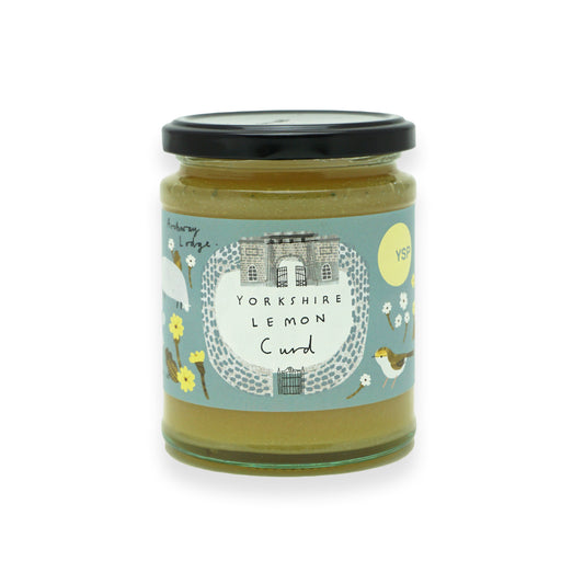 A glass jar of Yorkshire lemon curd with a black lid and a blue label that features illustrations of sheep, flowers and birds.