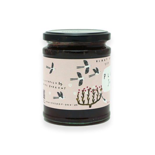 A glass jar with a black lid and pink label that features illustrations of birds and trees.