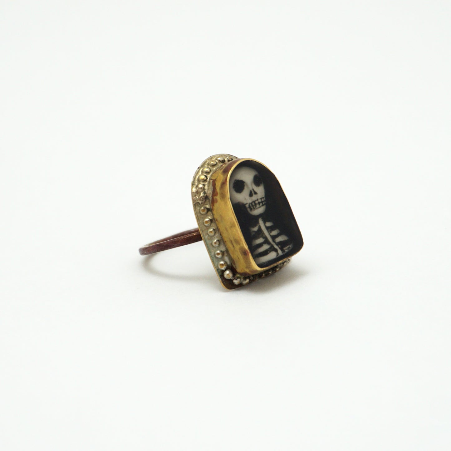 Ring with a hand painted skeleton design in a gold bezel on a white background