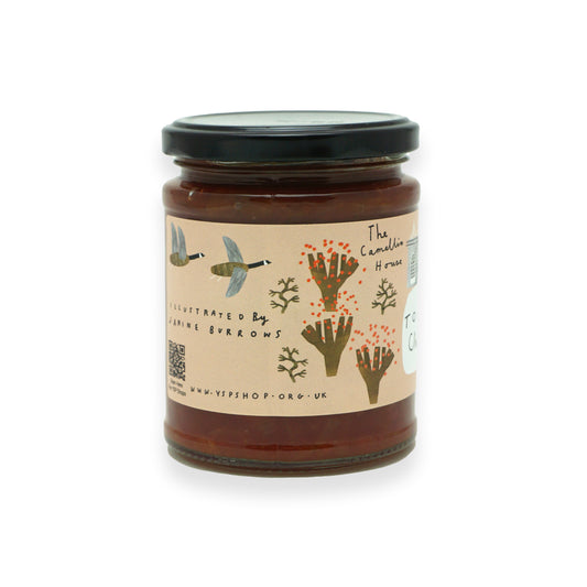 A glass jar with a black lid and orange label featuring illustrations of geese, trees and a camelia house.