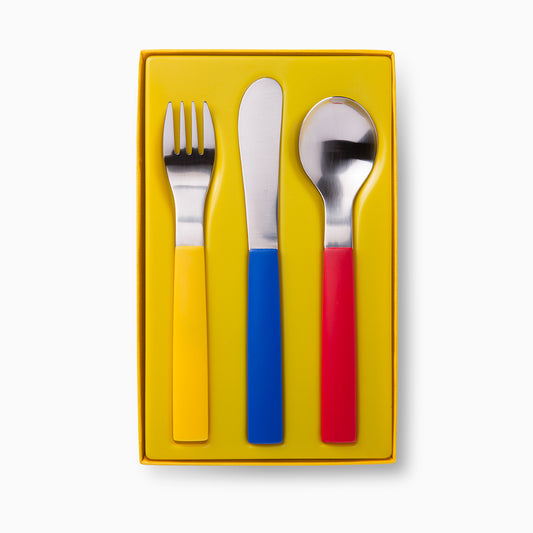 A boxed set of cutlery featuring a fork, knife, and spoon. Each utensil has a shiny metal head and a brightly coloured handle: the fork has a red handle, the knife has a blue handle, and the spoon has a silver head with a matching handle.