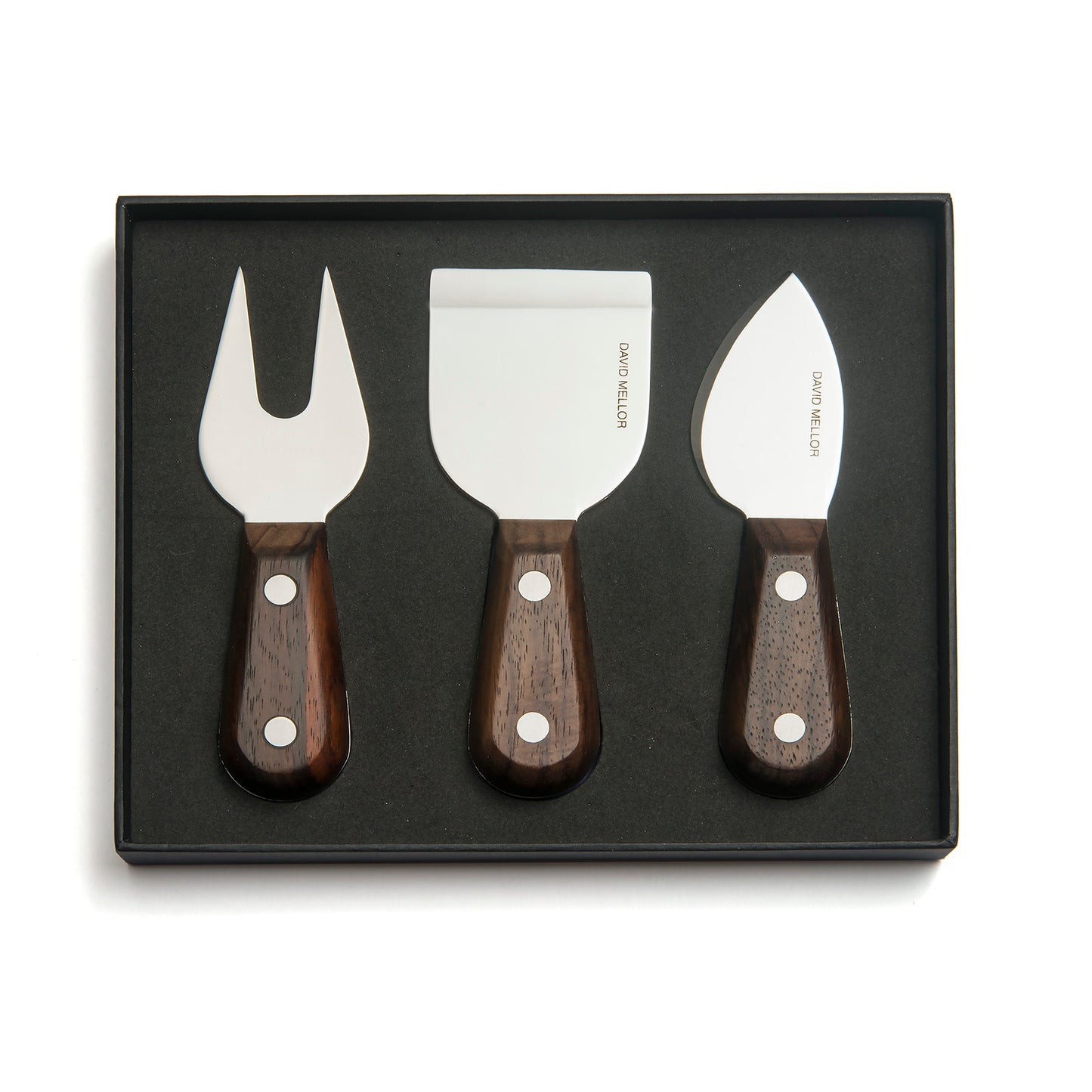 A set of three cheese knives displayed in a black box. The knives feature stainless steel blades and dark wooden handles, including a fork, a flat spatula, and a curved knife, all elegantly designed for serving cheese.