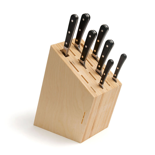 A wooden knife block with a slanted design, featuring several kitchen knives with black handles. The block is light in colour, showcasing a minimalist style, and the knives are neatly arranged in various slots.