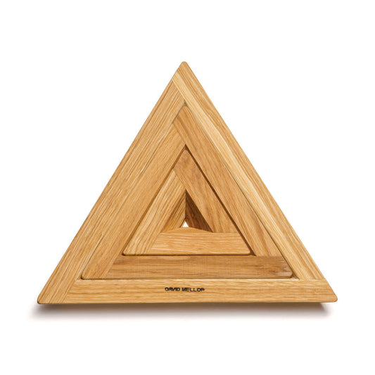 A wooden triangular trivet featuring three nested triangles of varying sizes, crafted from light-coloured wood. The design is minimalist and elegant, with a smooth finish, showcasing the natural grain of the wood. The base is marked with "David Mellor.