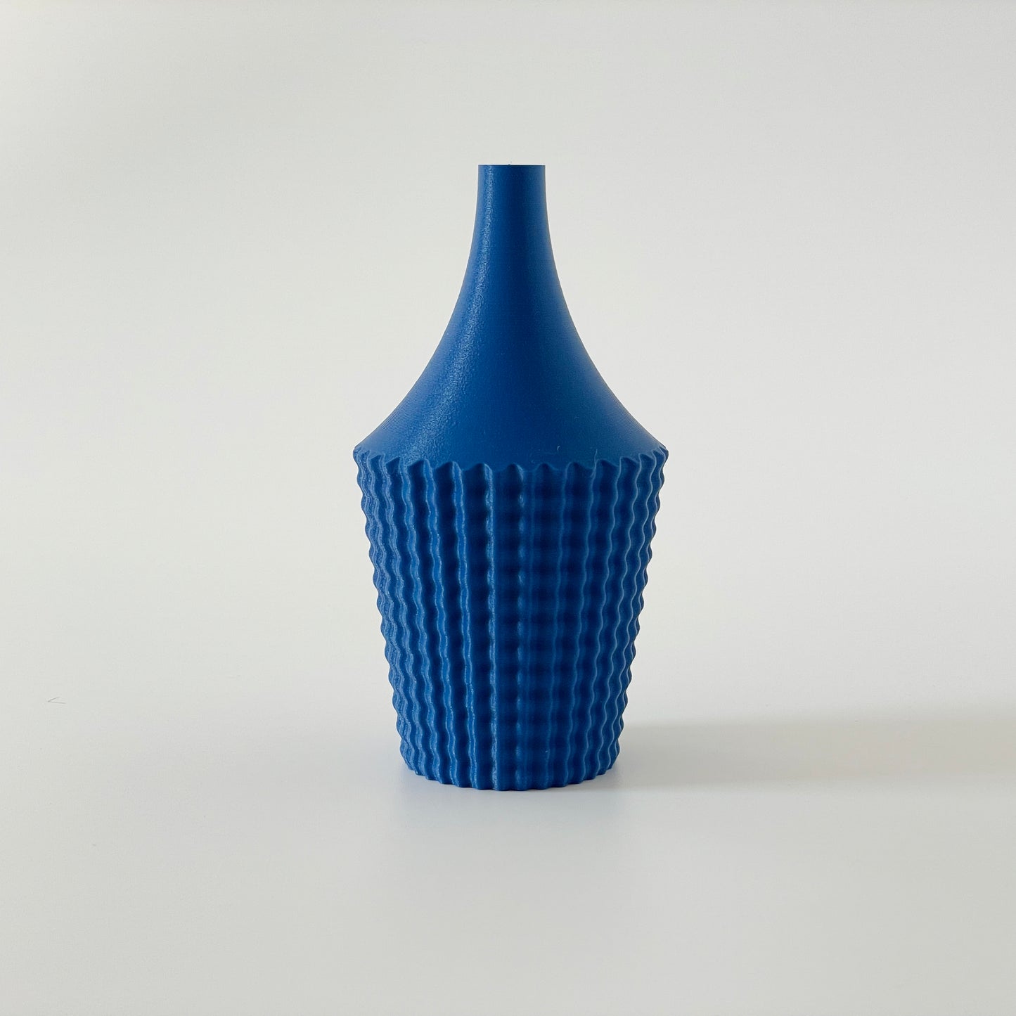 A blue 3D printed vase with a geometric ribbed design on a white background.