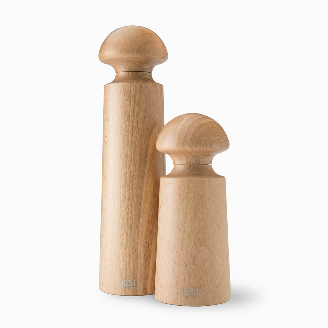 A pair of wooden pepper mills in a light natural finish. The taller mill has a cylindrical body with a rounded top, while the smaller one features a similar design but is noticeably shorter. Both have a sleek, minimalist aesthetic.