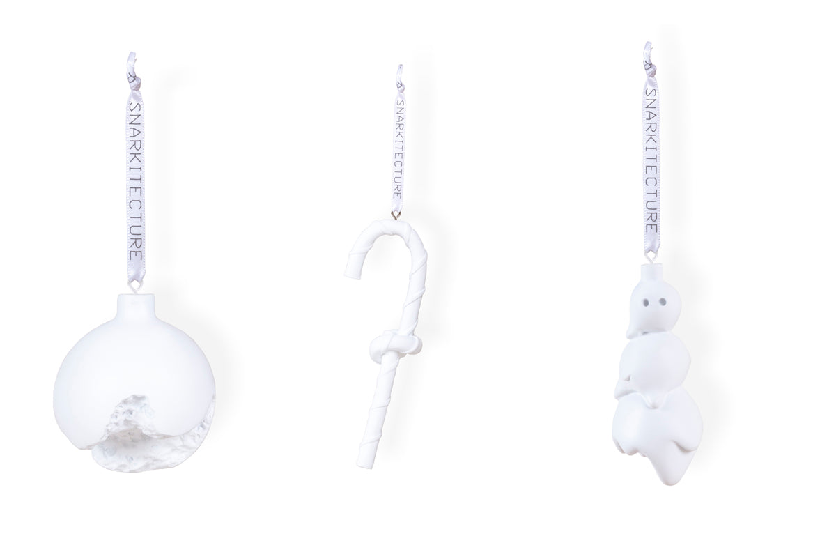 Three white Christmas ornaments hang against a plain background. From left to right: a textured round bauble, a twisted candy cane, and a snowman figure, each with a silver ribbon for hanging.