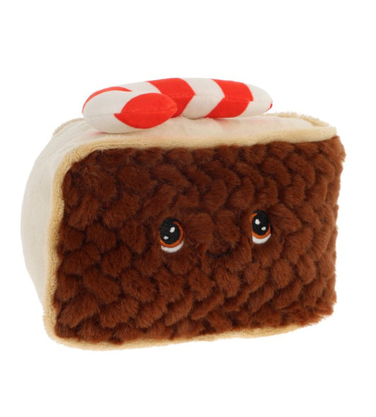 A plush toy shaped like a slice of Christmas cake, with a brown fuzzy front, cream-colored edges, embroidered eyes, and a red-and-white striped top detail, shown on a plain white background.
