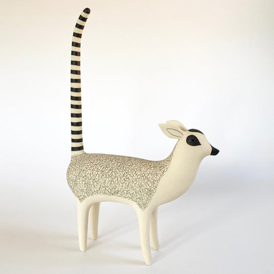 Decorative animal sculpture of a lemur with a striped tail on a white background