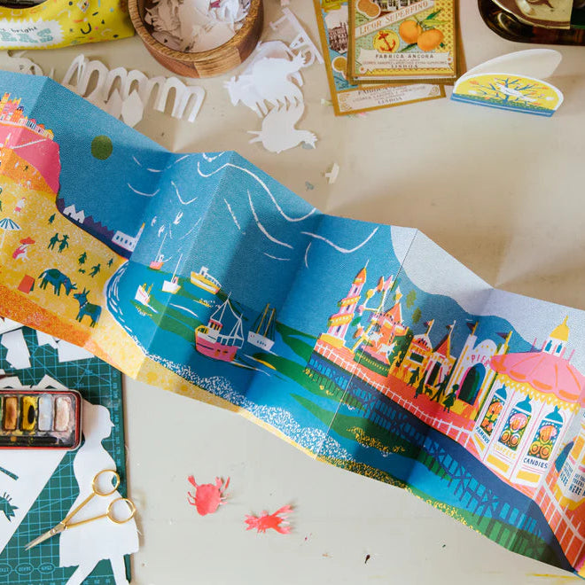 Colorful children's book with illustrations on a table with art supplies.