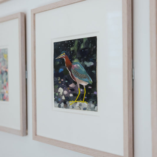 Framed artwork of a bird on a white wall