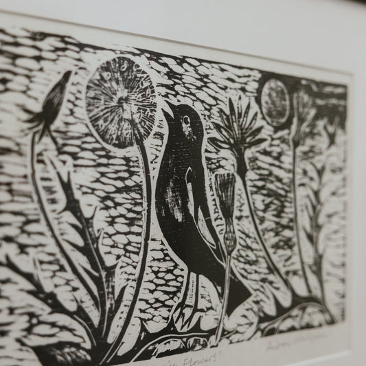 Black and white linocut print of a bird and dandelions.