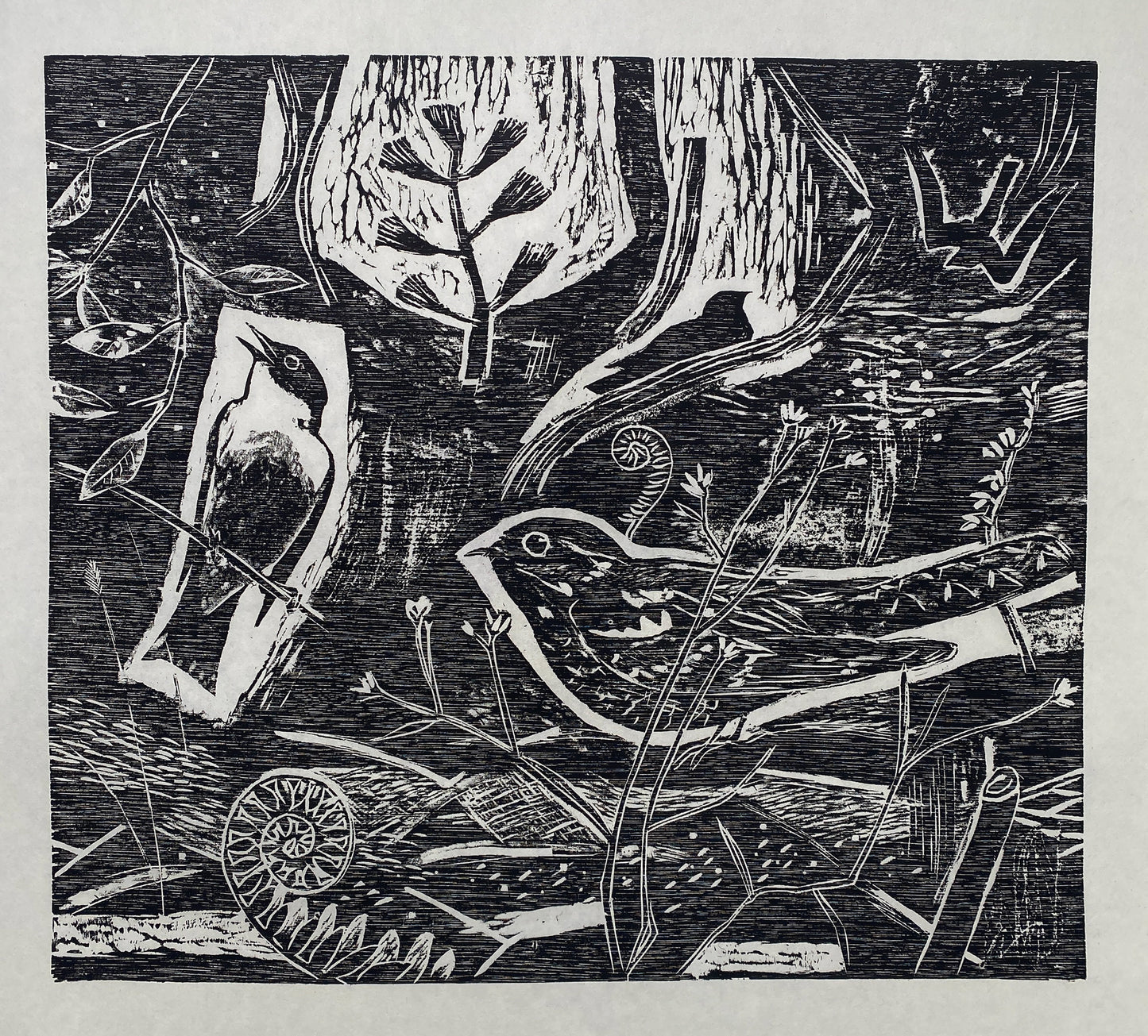 A black wood cut print showing two birds sitting on foliage and branches surrounded by more textured foliage.