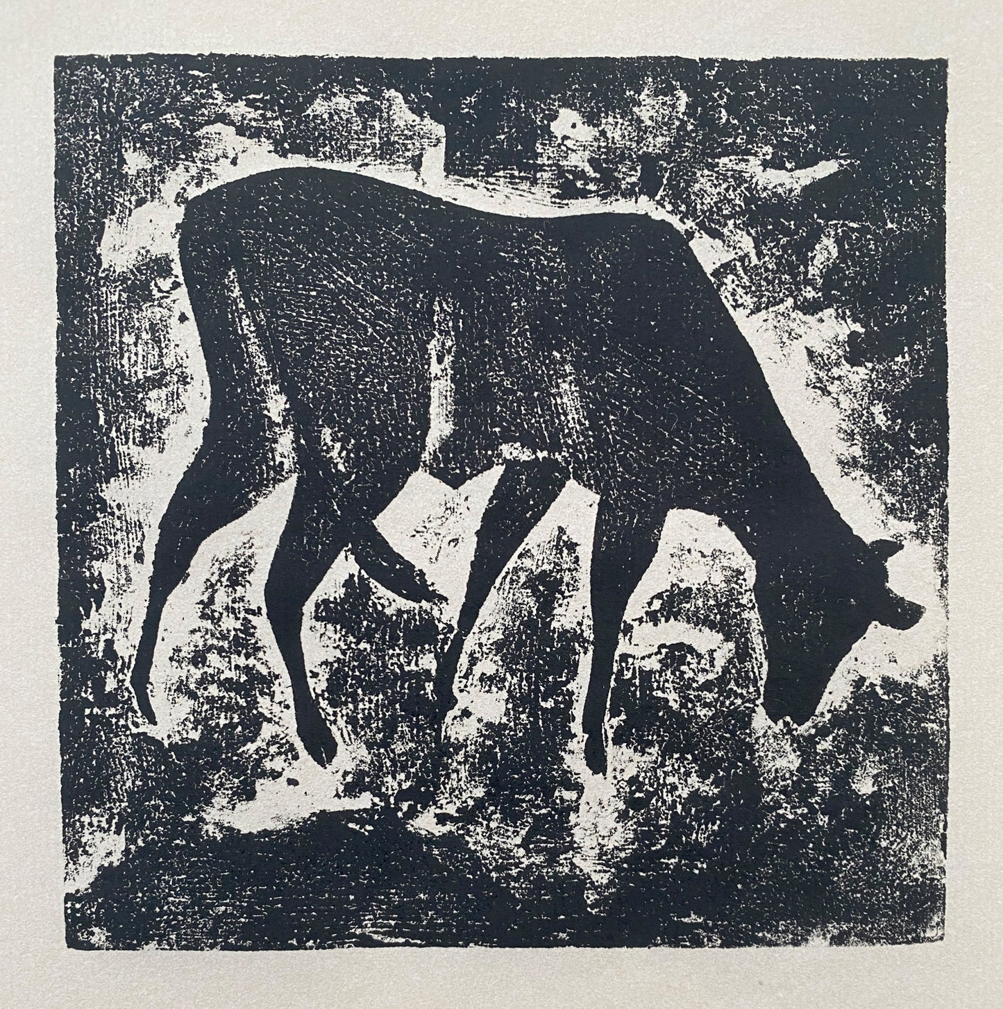 A black wood cut print with a single cow feeding with a textured background.
