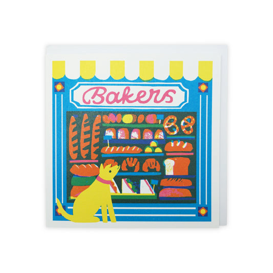 A vibrant illustration of a bakery storefront, featuring a variety of baked goods like bread and pastries. A cheerful yellow dog sits in front, adding a playful touch to the scene, framed by a bright blue background and colourful signage.