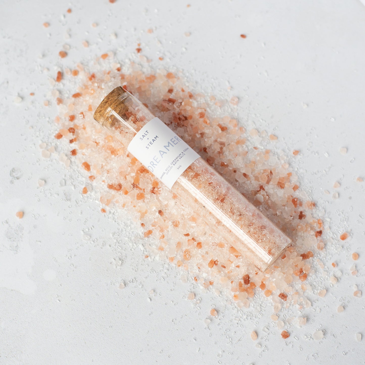 Glass jar filled with pink Himalayan salt on a light gray surface