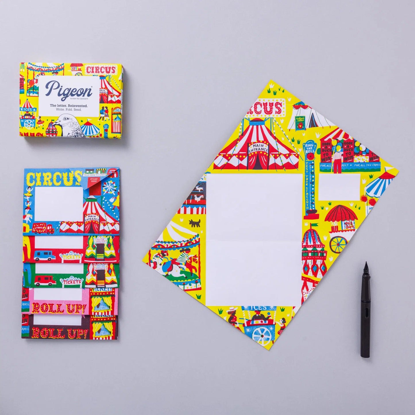 A vibrant circus-themed stationery set featuring a colourful box and a matching notepad. The notepad has a blank space for writing, surrounded by illustrations of circus tents, performers, and carnival elements. A black pen is placed beside it.