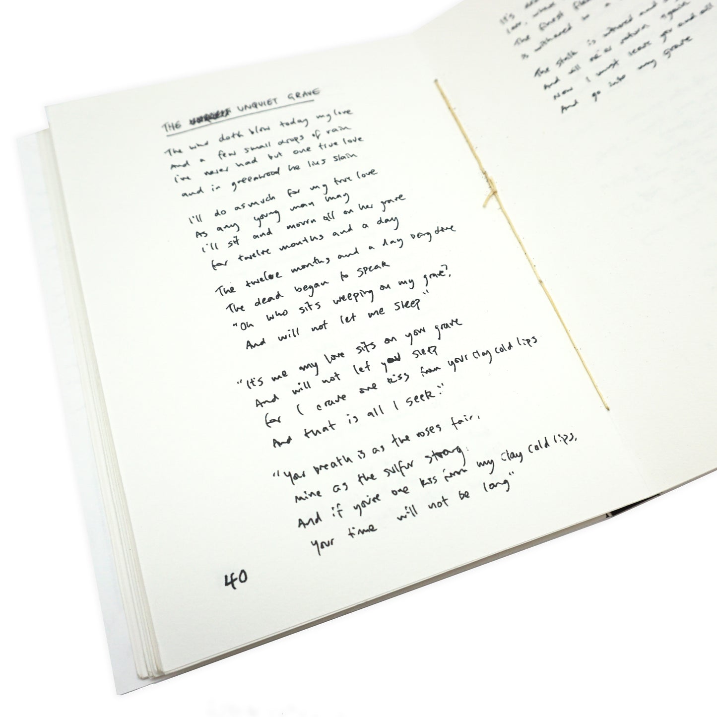 Handwritten text on a white card with a gold hand sewn spine in the middle.