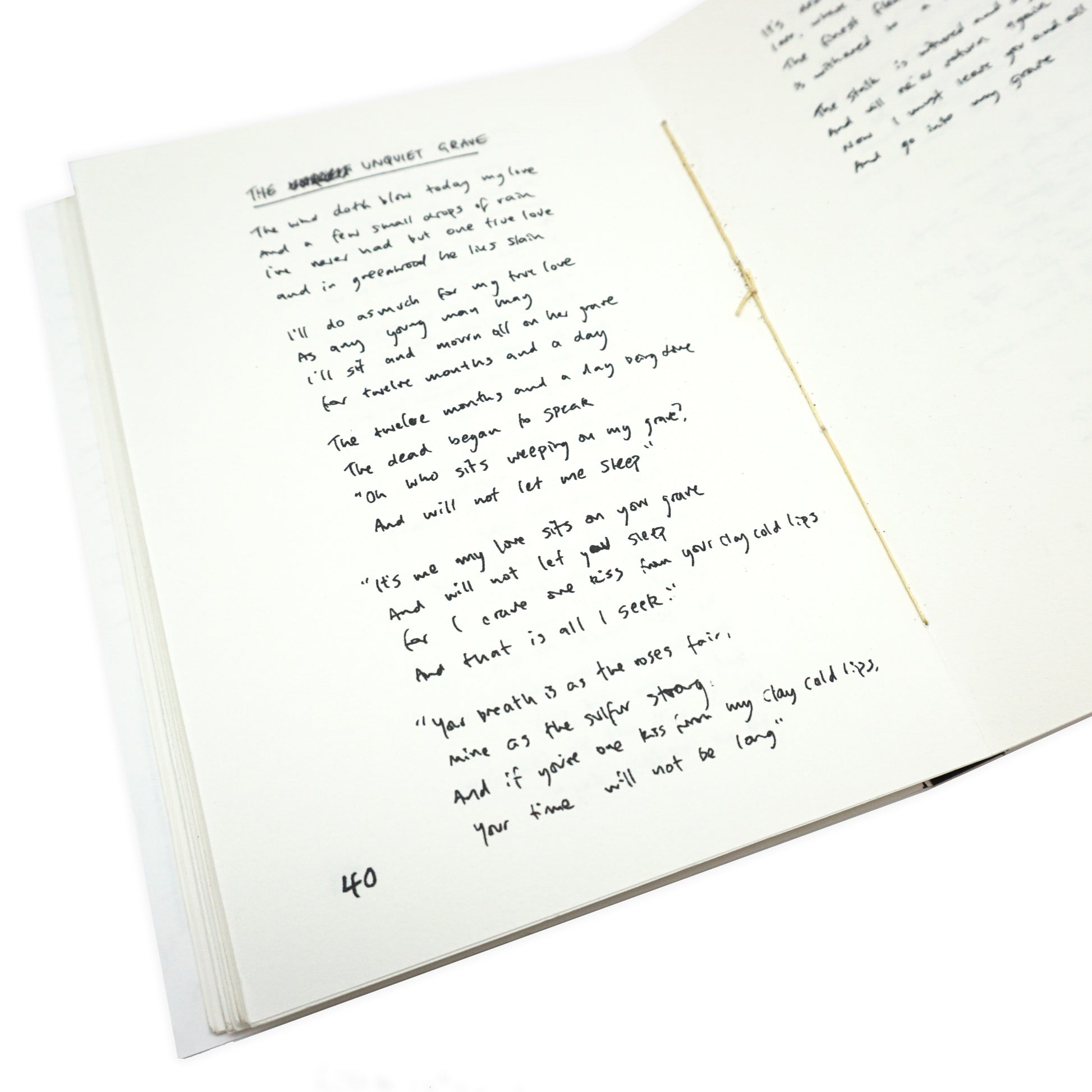 Handwritten text on a white card with a gold hand sewn spine in the middle.