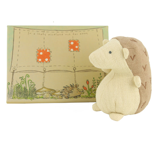 Plush hedgehog toy with a decorative box featuring illustrations on a white background