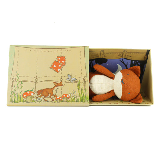 Plush fox toy in a box with a forest-themed illustration on a white background
