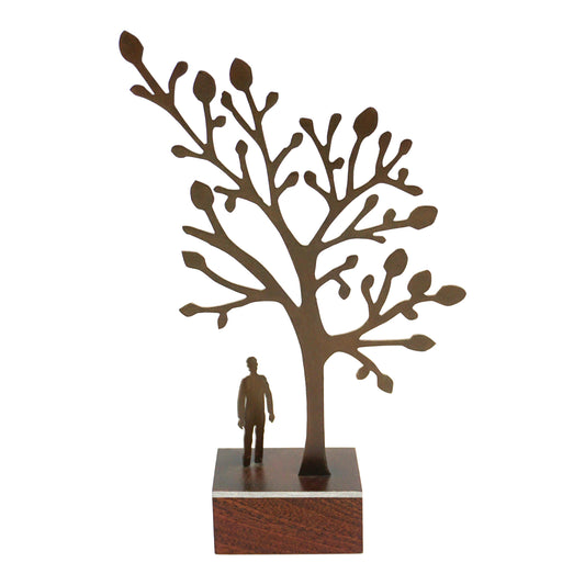Decorative sculpture of a tree with a person underneath looking up on a plain white background.