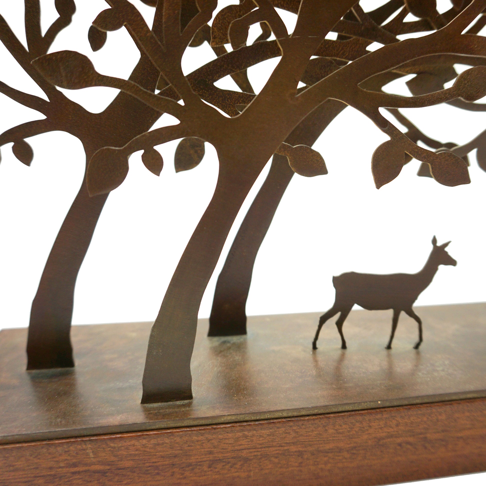 A steel and wood mini sculpture featuring laser cut trees that form a tunnel where a single deer sits in the middle.