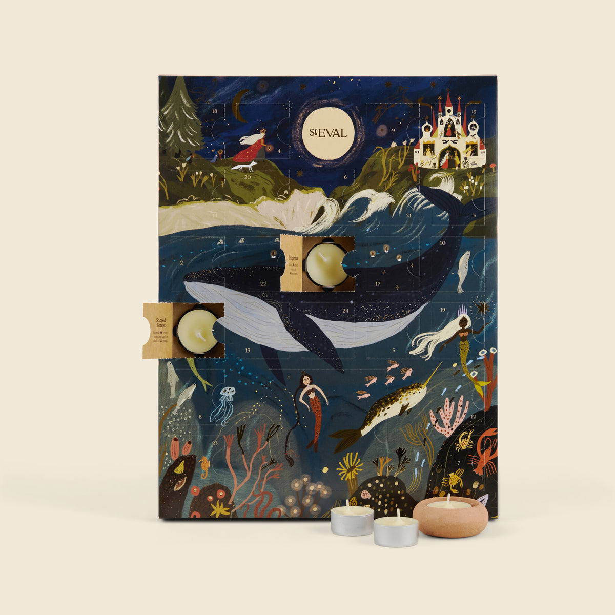 A St Eval advent calendar with a whimsical underwater illustration featuring a whale, mermaids, sea creatures, and a castle under a full moon. The calendar is shown open with two small tea light candles placed in front on a light beige background.