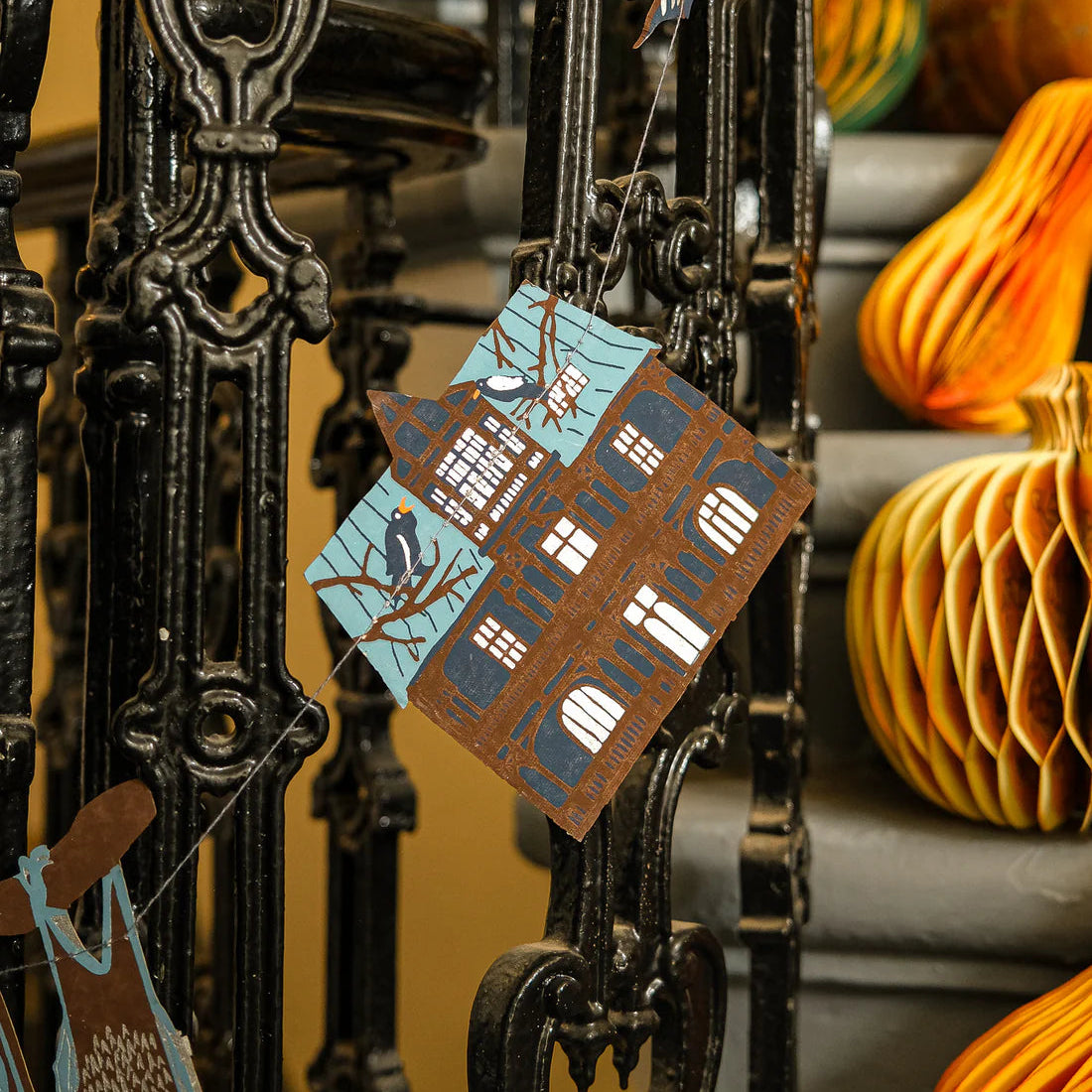 Decorative Halloween-themed garlands on a stand with pumpkins in the background.