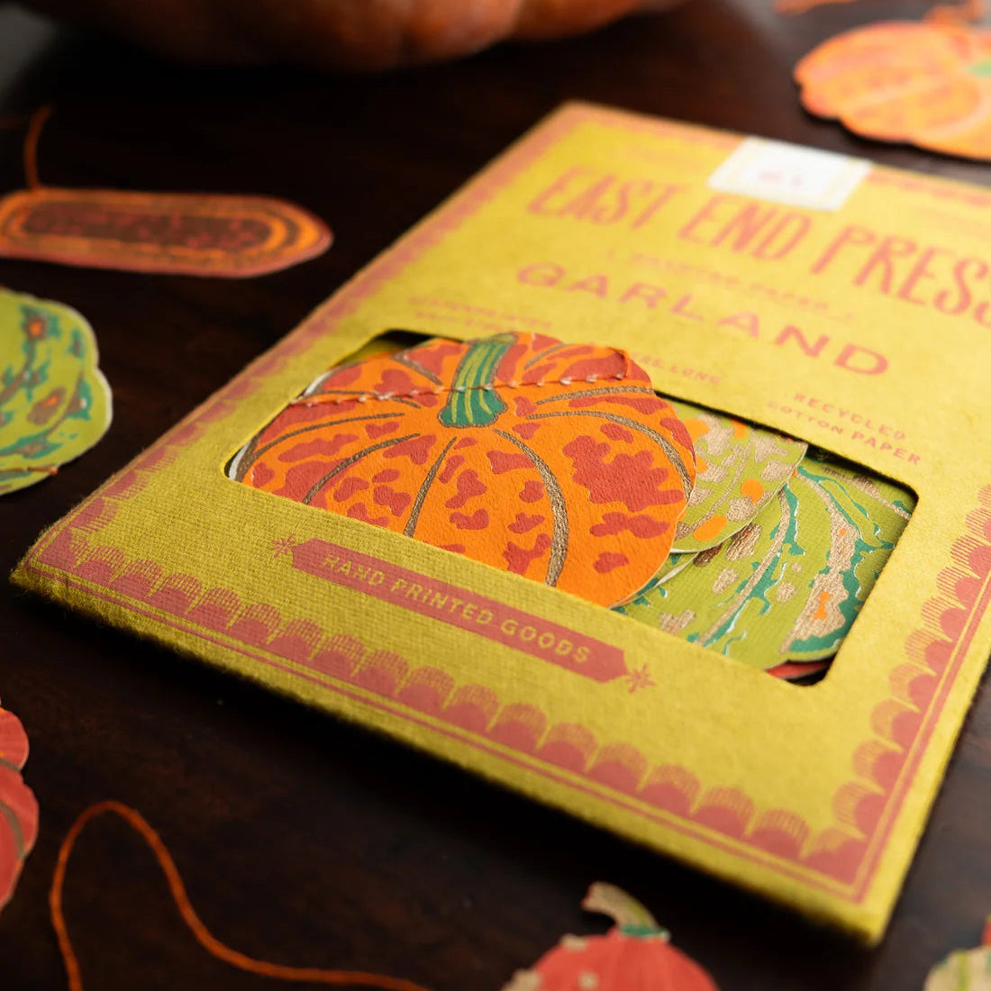 Boxed Halloween-themed garland with pumpkins on a dark surface.
