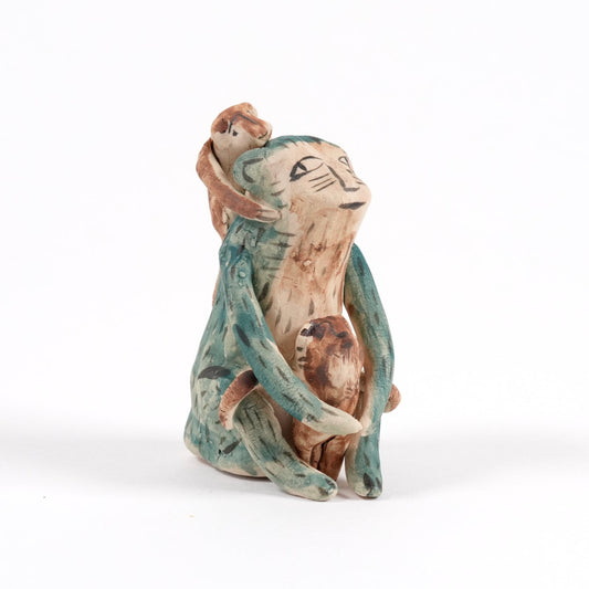 Small ceramic monkey whistle on a white background. The monkey is green in colour with two smaller monkeys on it's front and back.